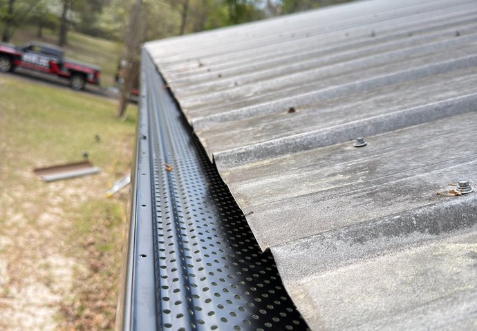 Gutter guard mesh installed to keep debris out of a gutter under a metal roof