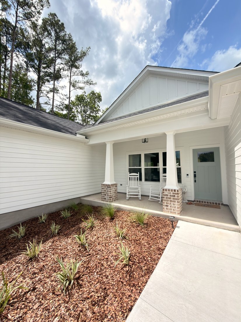 White farmhouse with a covered rocking-chair porch and seamless gutters