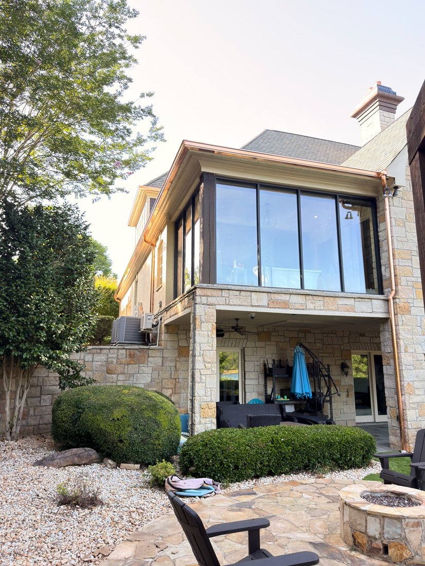 Stone home with copper seamless gutters over a covered patio