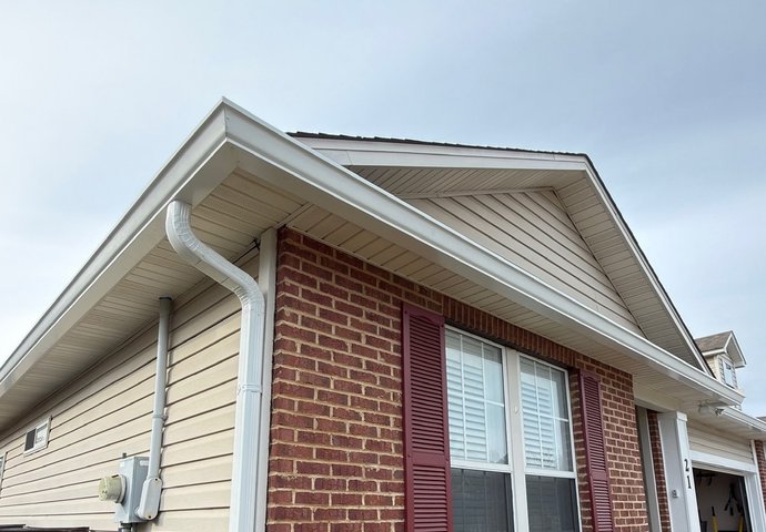 New white seamless gutter and downspout installed on a brick home