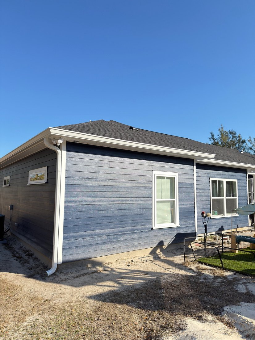 Gray home with seamless gutters and a downspout