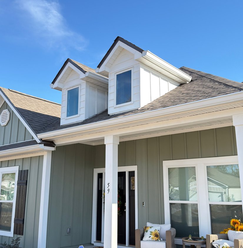 White gutters installed along the roofline of a two-dormer farmhouse-style home